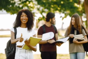 Three international students standing in a park and holding a bo